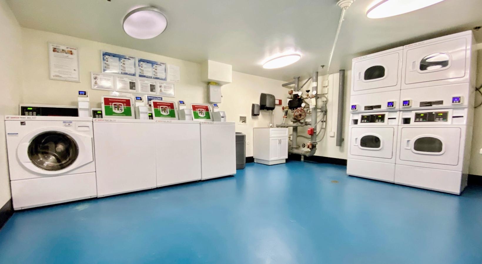 Washers and dryers available a room with washing machines and a blue floor